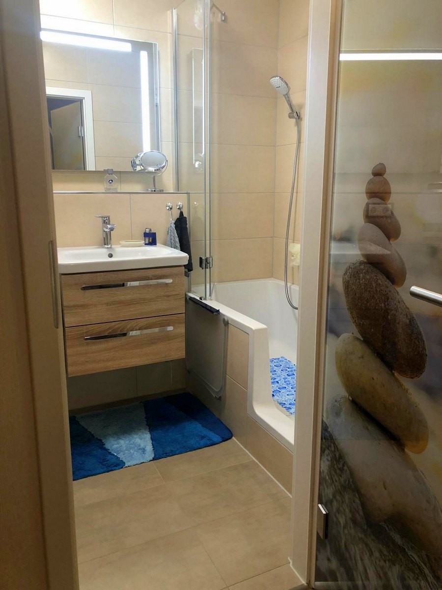 Waschtisch, großer Spiegel mit viel Licht und Duschbadewanne auf engsten Raum.