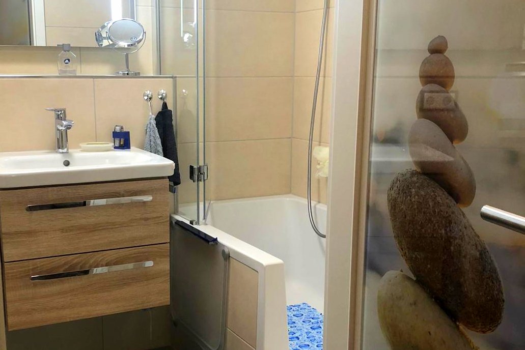 Waschtisch, großer Spiegel mit viel Licht und Duschbadewanne auf engsten Raum.