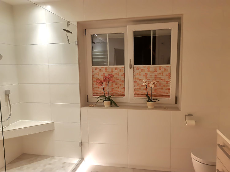 Der Eckduschsitz und die durchsichtige Duschtrennwand sorgen für klare Linien in diesem Bad.